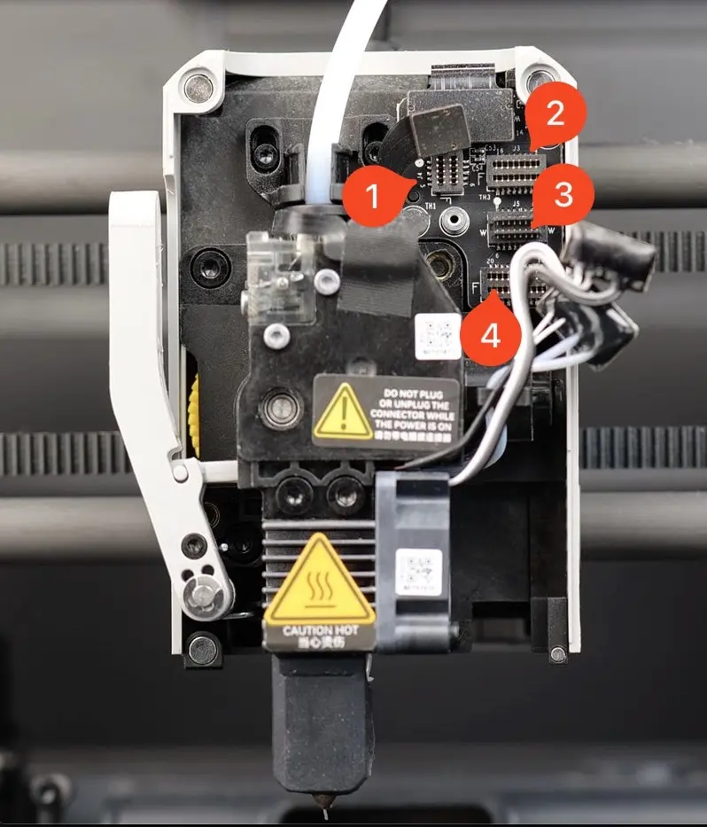 Extruder- og hotend-ledninger frakobles, fladkablet til filamentsensoren markeret