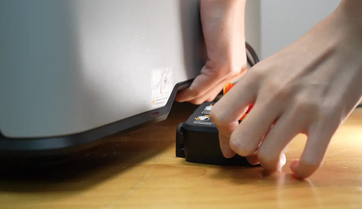 Printeren løftes for at placere nødstopknappens clips
