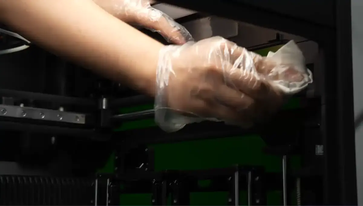 Glidestængerne på Y-aksen rengøres med en non-woven klud