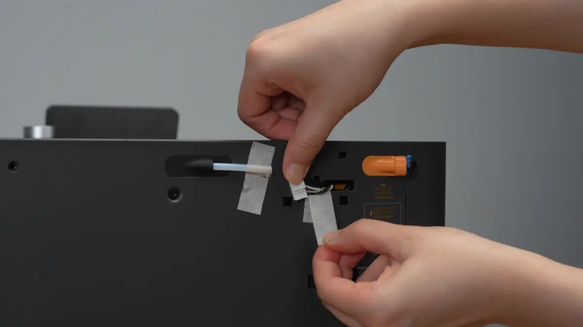 Tapen der holder kabel og PTFE-slange fjernes