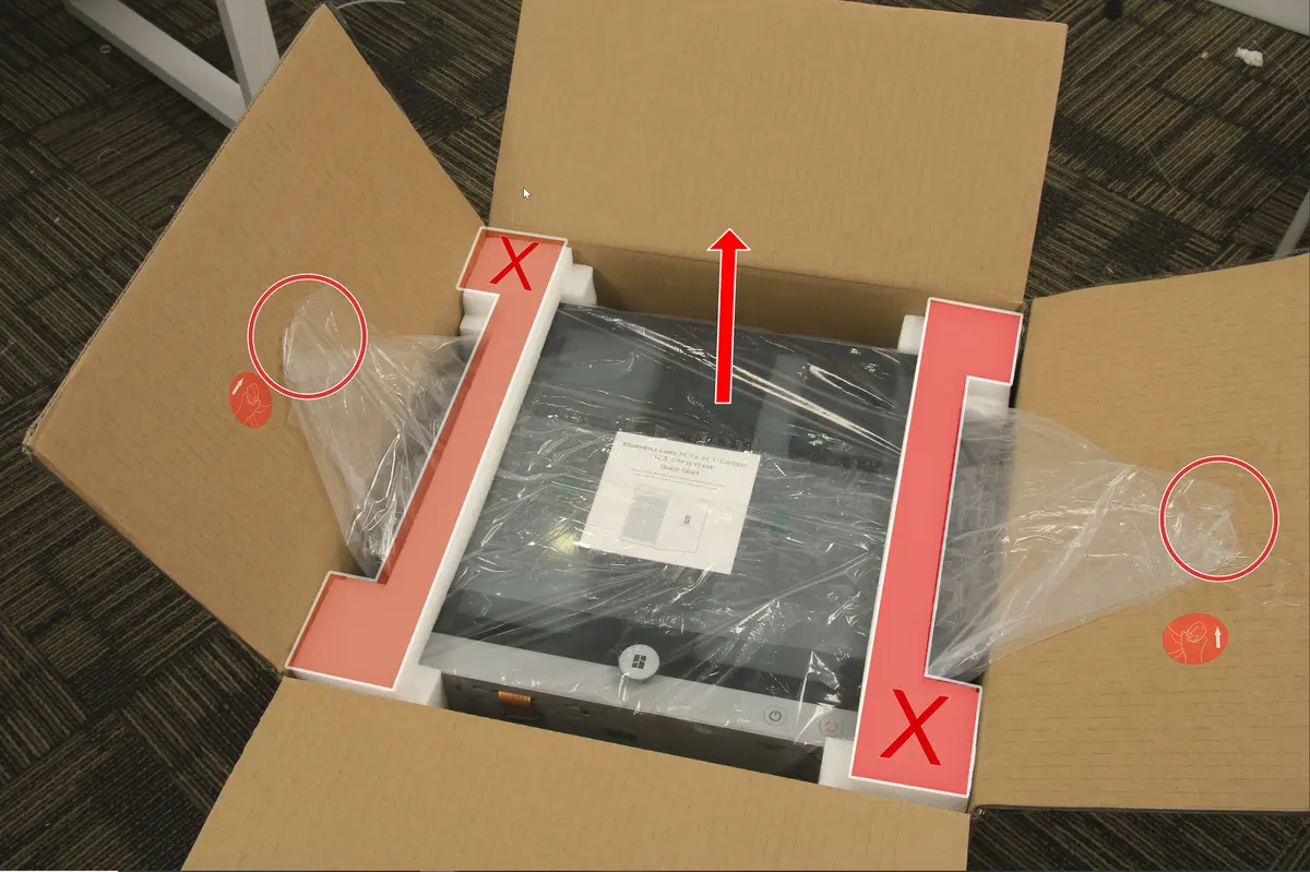 Printeren tages ud af kassen ved hjælp af plastikposens håndtagsstropper