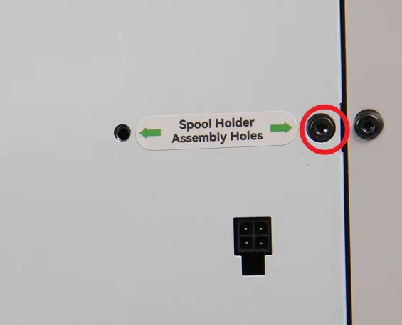 Skruen bag på printeren fjernes for at forberede spoleholderens montering